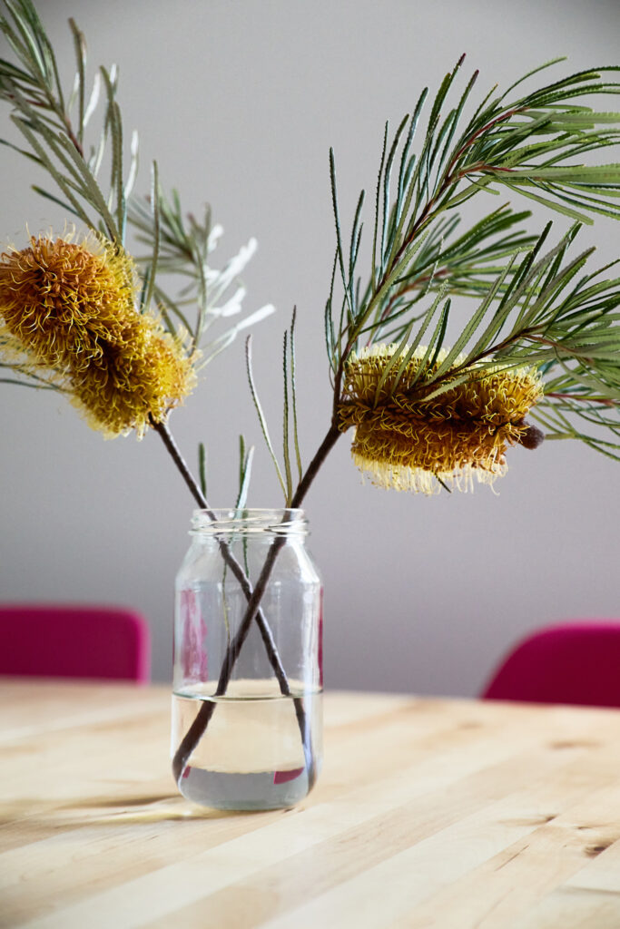 Melbourne Siomas Management's Melbourne property stay. Image depicts a styled vase in the living area, featuring yellow native flowers.