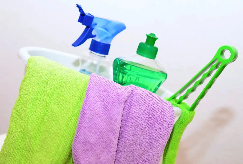 Our Services Image of cleaning products in a bucket with a green and lilac microfibre cloth.